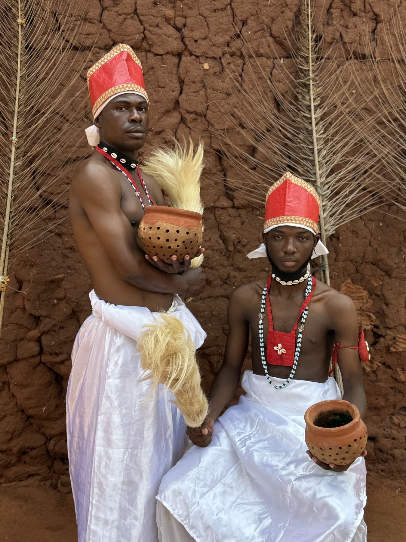 Dos adeptos del vodún con gorro rojo, danza Gelede, Benín