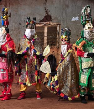 Cuatro mascaras egungun ante una casa de tierra, Benin
